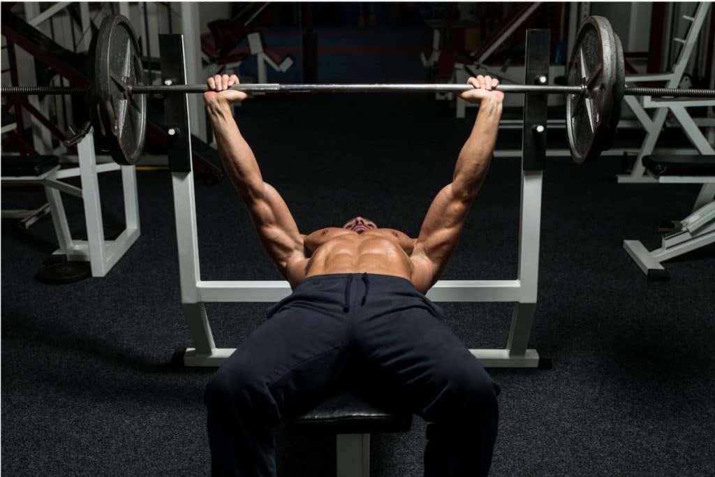 Man lying on bench press lifting weights